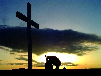 A picture of a man kneeling before a cross